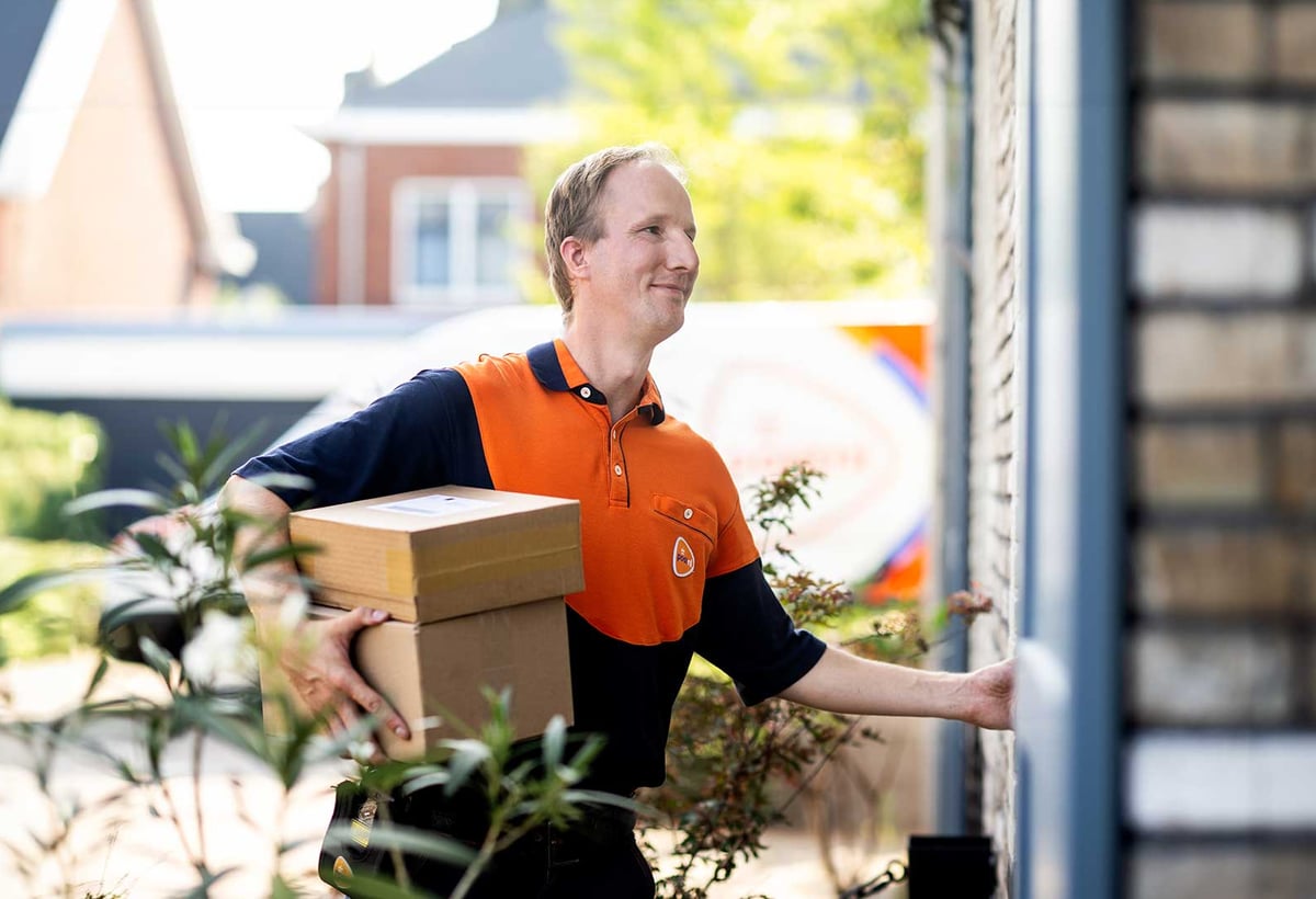 PostNL-bezorger met pakketten bij een woning